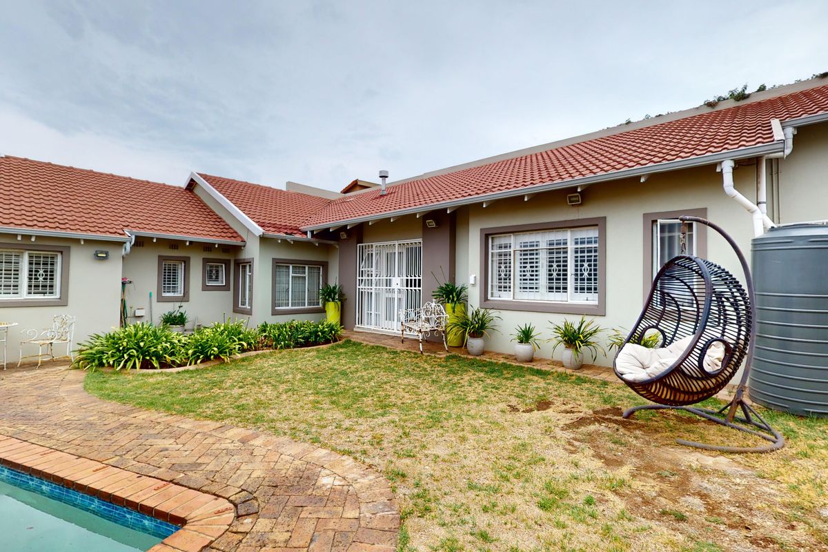 Rear view of the property featuring a swimming pool, brick paved pathway, and a water storage tank set against a landscaped garden area.