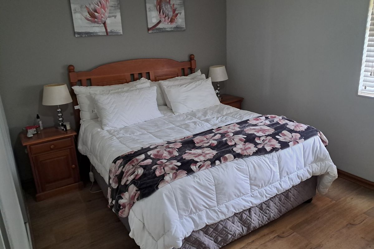 A well-maintained bedroom featuring wood-look flooring and neutral wall tones, providing a comfortable and functional living space.