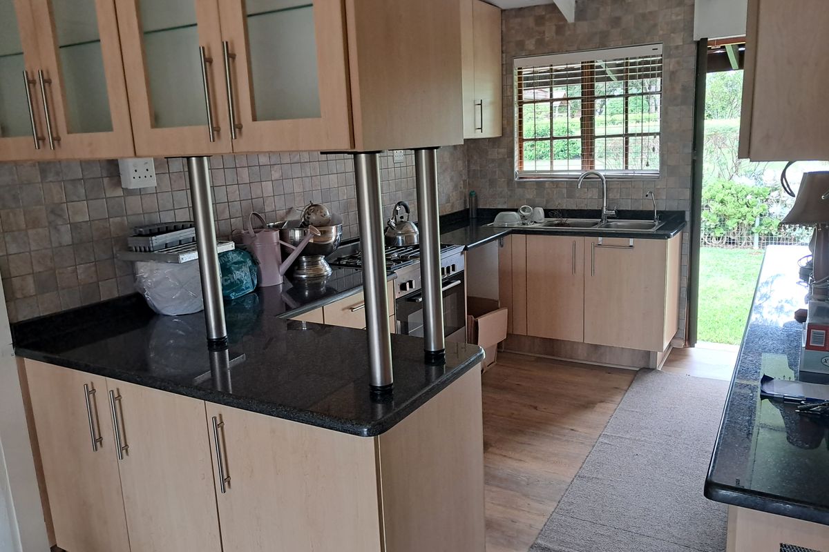 A functional kitchen featuring light wood-toned cabinetry, dark granite countertops, a built-in oven, and a tiled backsplash with direct access to the garden.