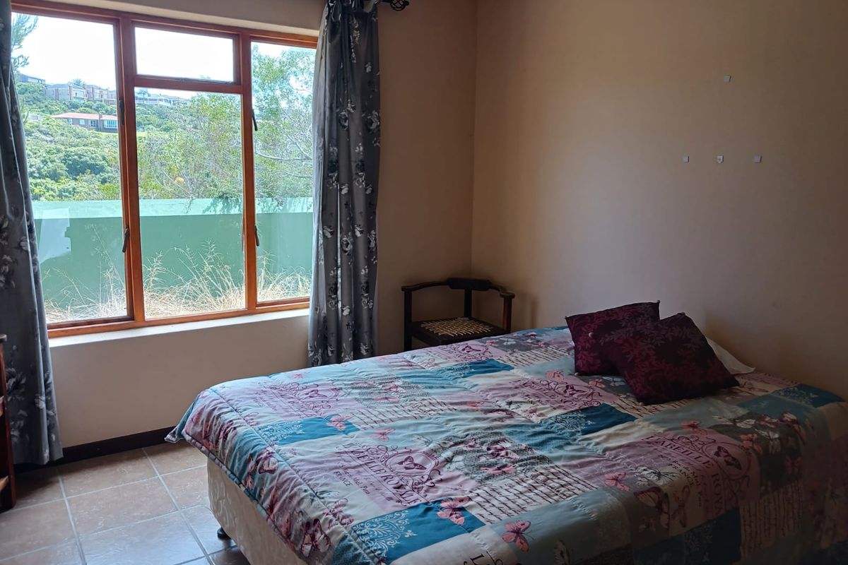 A bedroom featuring tiled flooring and a large window with natural light, offering a view of the surrounding landscape.