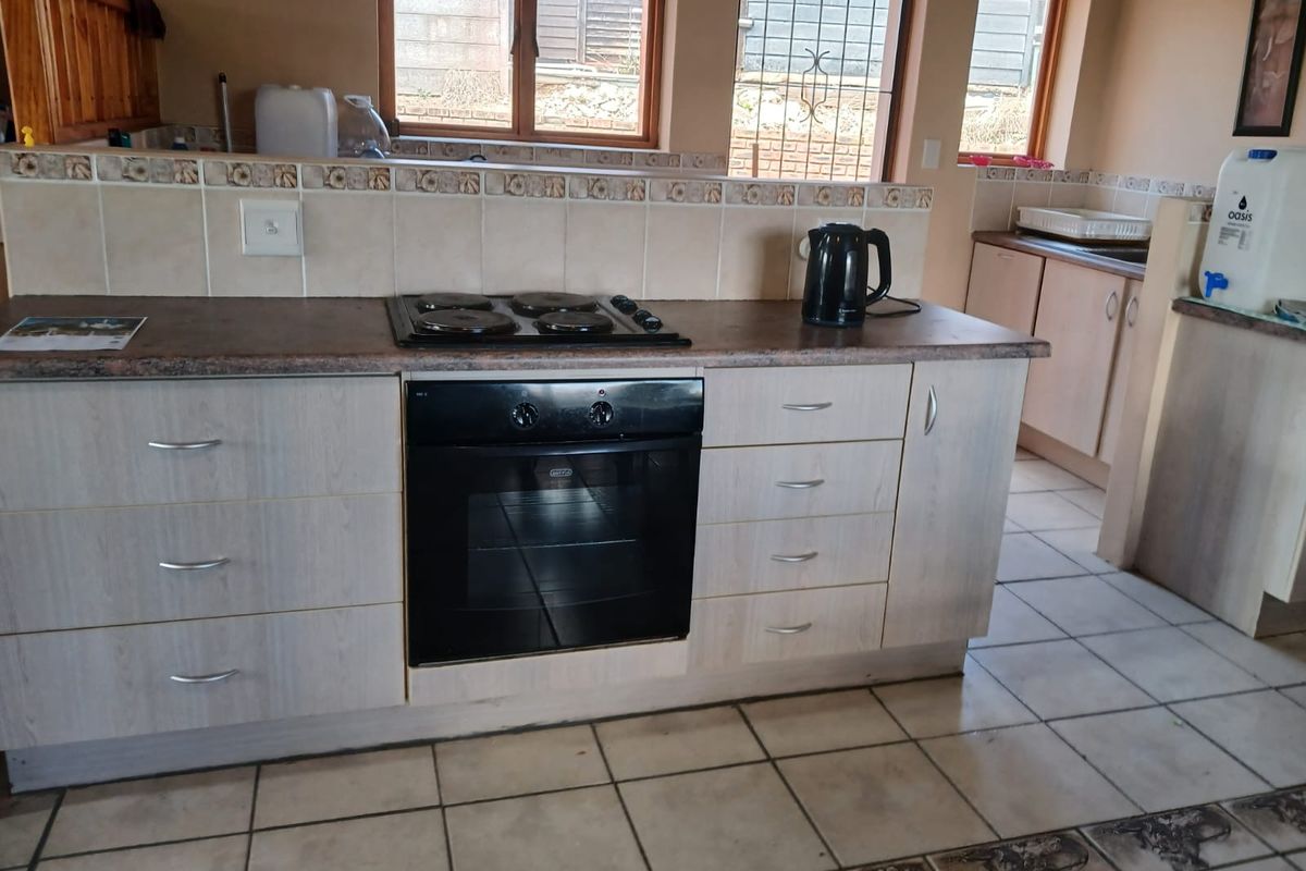 A functional kitchen area featuring built-in cabinetry, a laminate countertop, a fitted electric oven and hob, and tiled flooring.