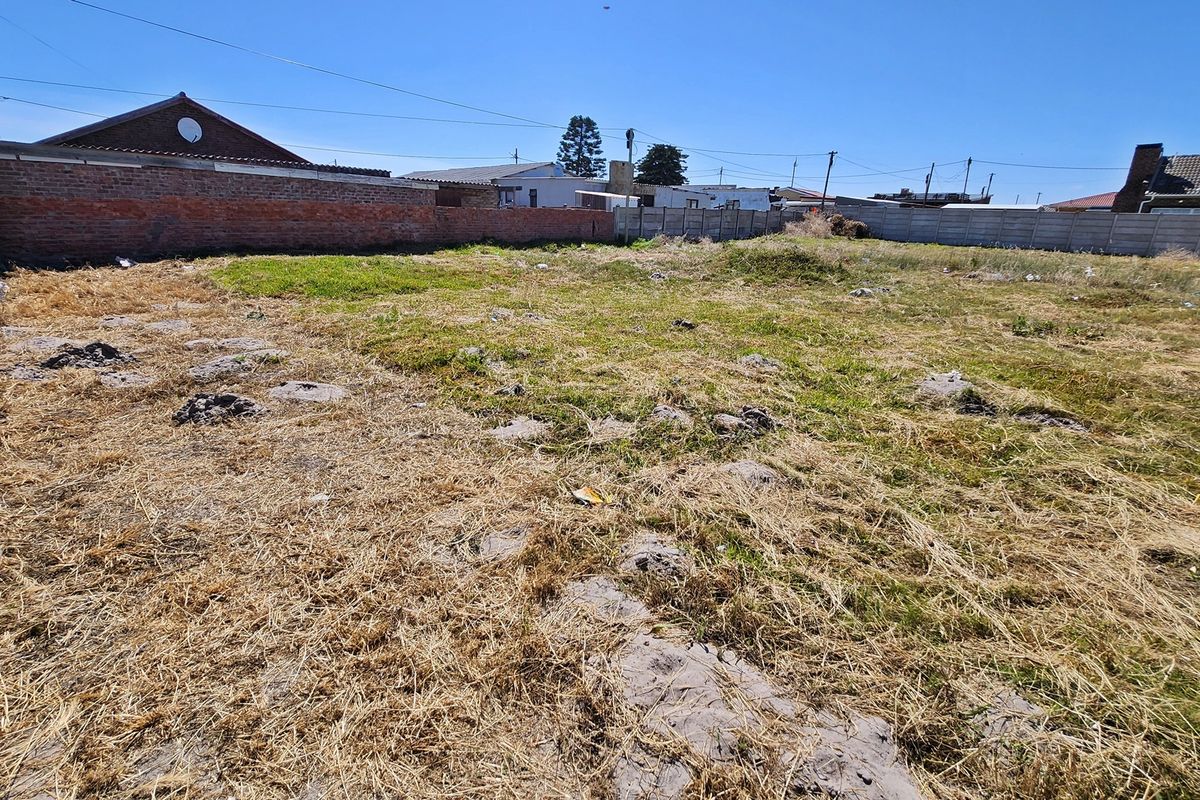 A vacant residential plot featuring perimeter brick and precast concrete boundary walls with existing chain link fencing.