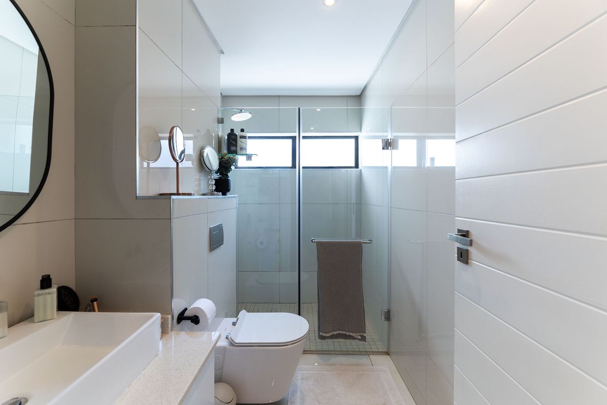Modern bathroom featuring a wall-hung toilet, glass shower enclosure, and a sleek countertop basin with stone vanity top.
