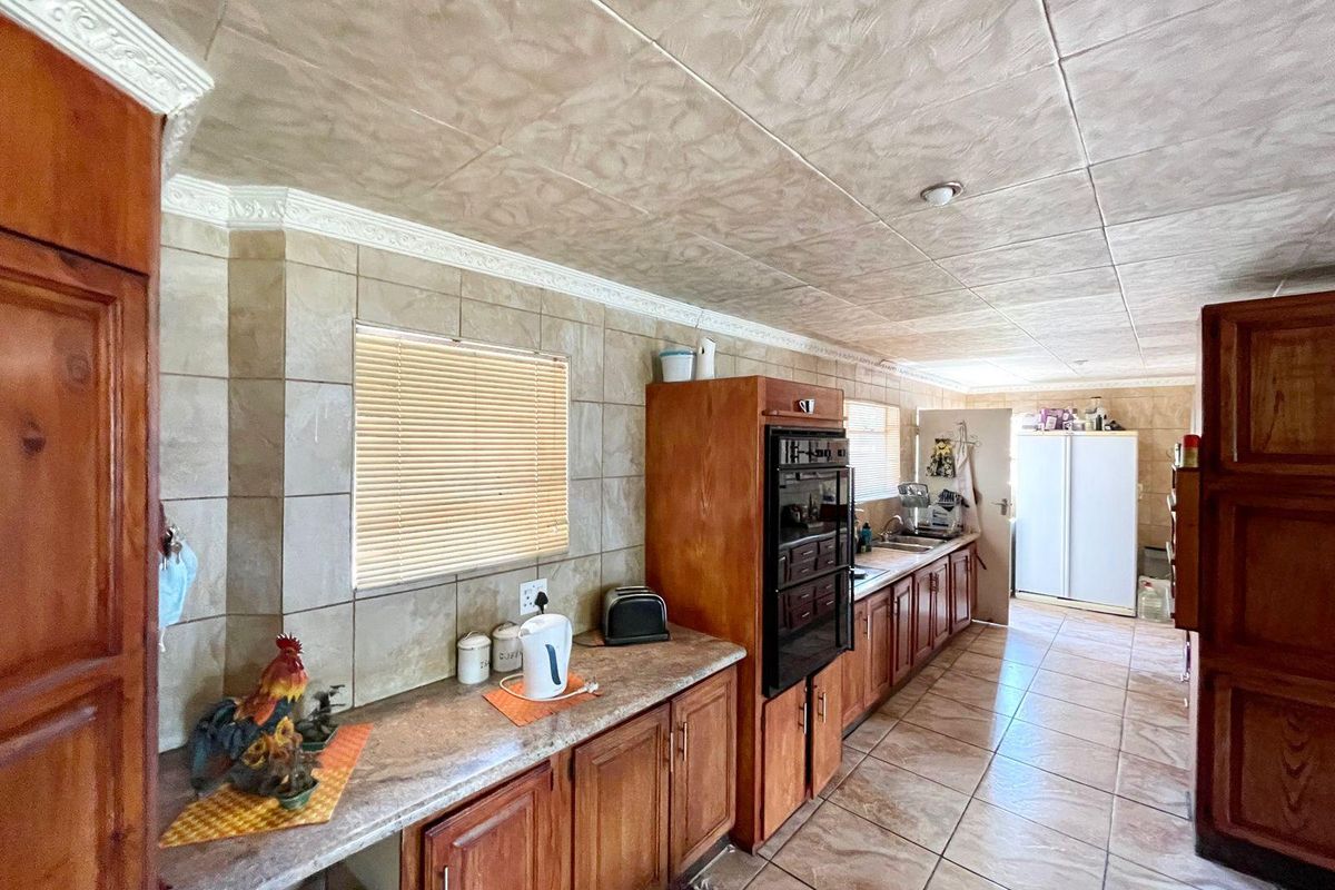 A functional kitchen featuring wooden cabinetry, tiled walls, and a built-in oven, offering a traditional layout with ample counter space.