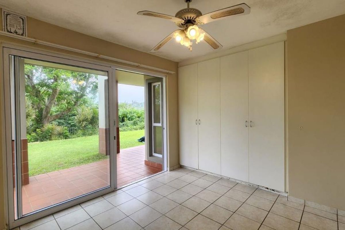 Empty bedroom featuring tiled flooring, built-in cupboards, and a sliding glass door providing direct access to an outdoor patio area.