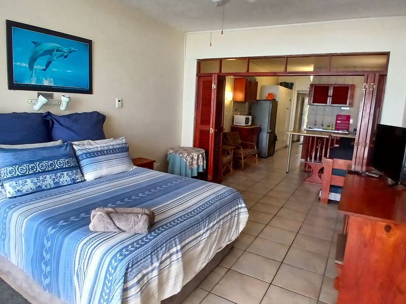 Open-plan studio apartment featuring a combined bedroom and kitchen area with tiled flooring and folding room dividers.