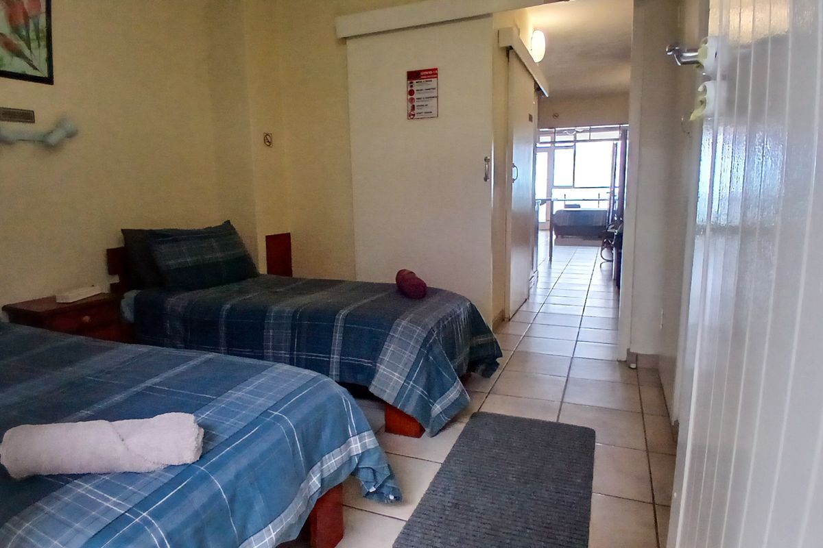 A bedroom featuring tiled flooring and a sliding door leading to an adjacent living area.