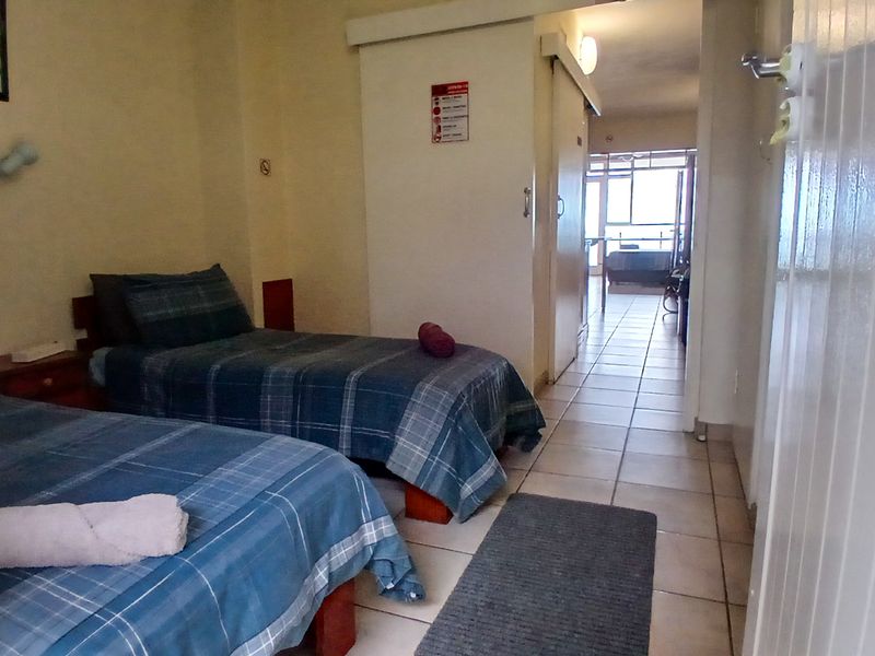 A bedroom featuring tiled flooring and a sliding door leading to an adjacent living area.