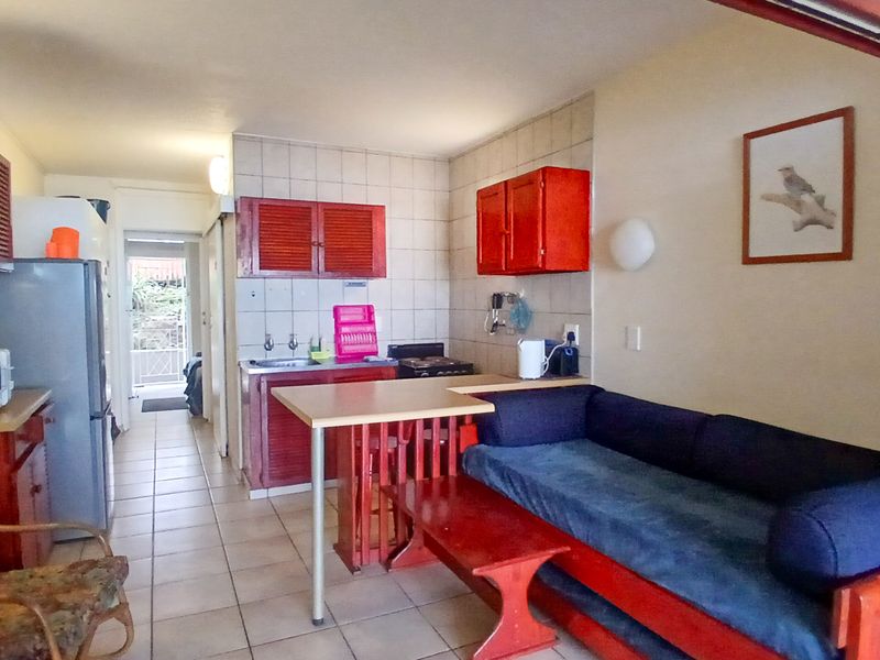 Open-plan living and kitchen area featuring tiled flooring, built-in cabinetry, and a functional layout connecting to the rear entrance.