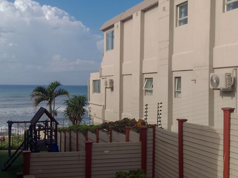 Rear exterior view of the apartment building featuring boundary fencing, electric security, and ocean views.