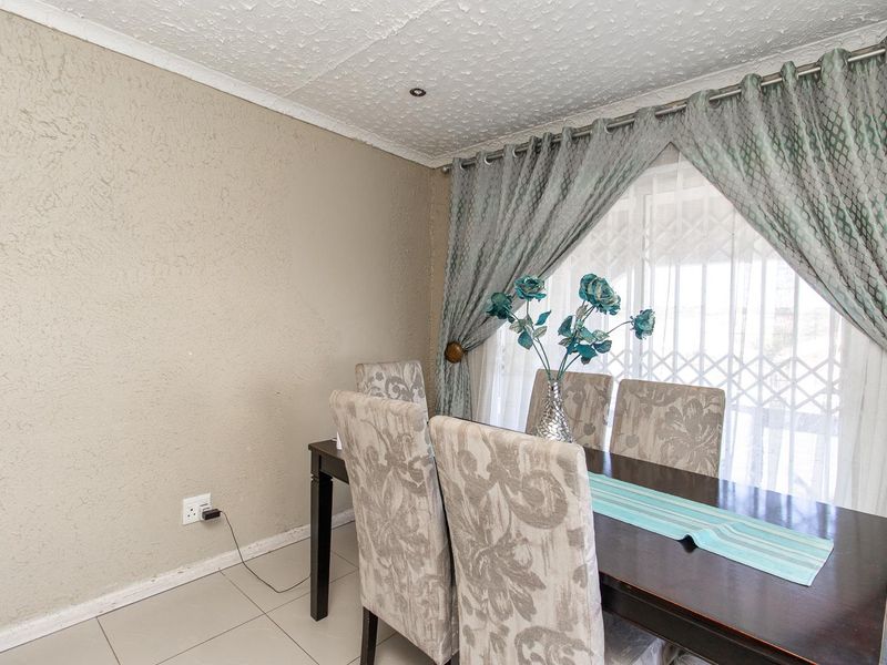 A dining area featuring tiled flooring, textured ceiling, recessed lighting, and a window fitted with a security gate.