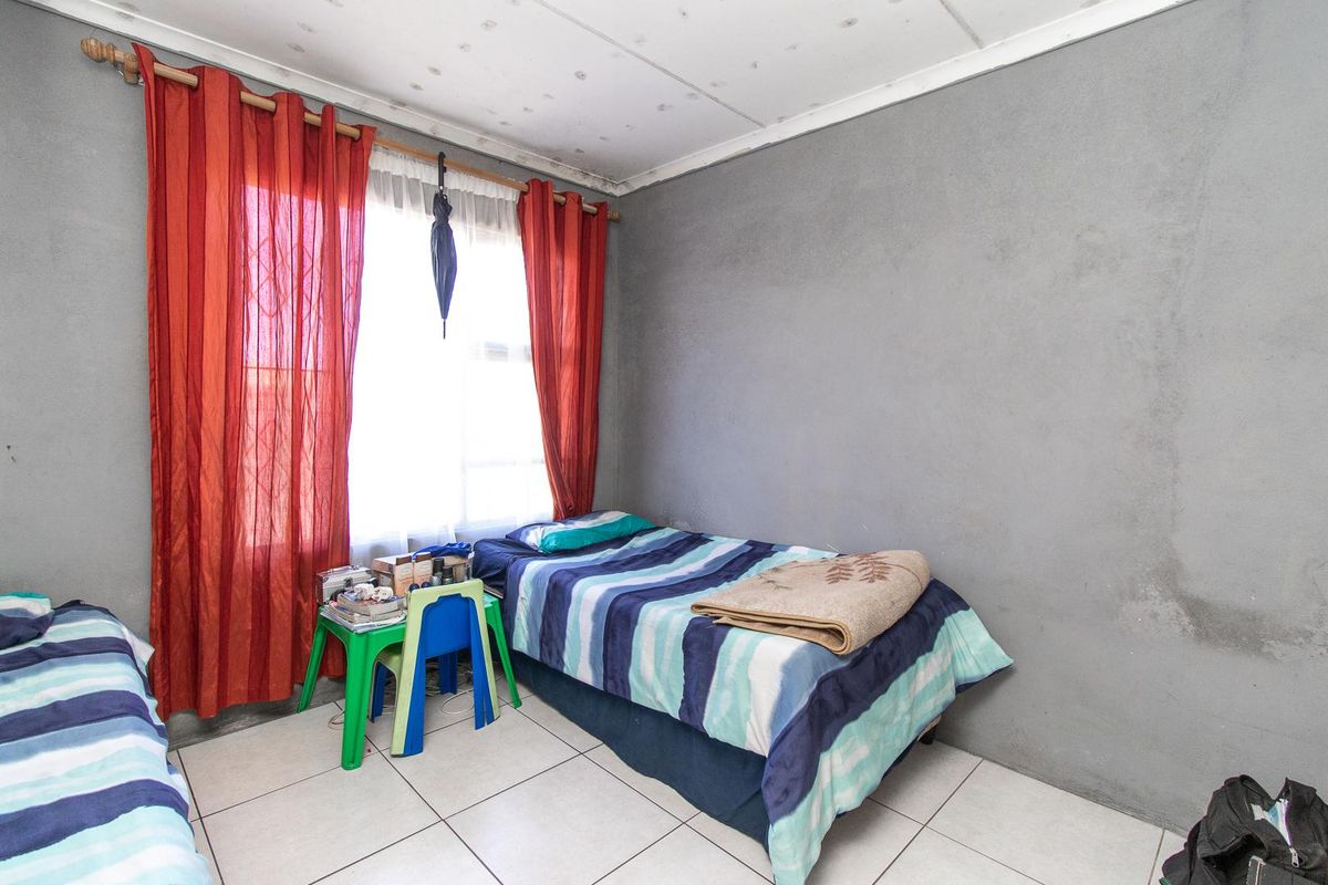 A bedroom featuring tiled flooring and a ceiling tile finish, currently showing signs of wear and wall staining.