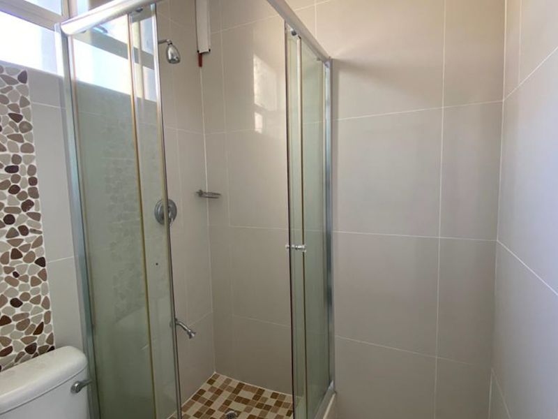 A clean bathroom featuring a glass-enclosed shower, tiled walls with decorative accents, and a standard toilet.