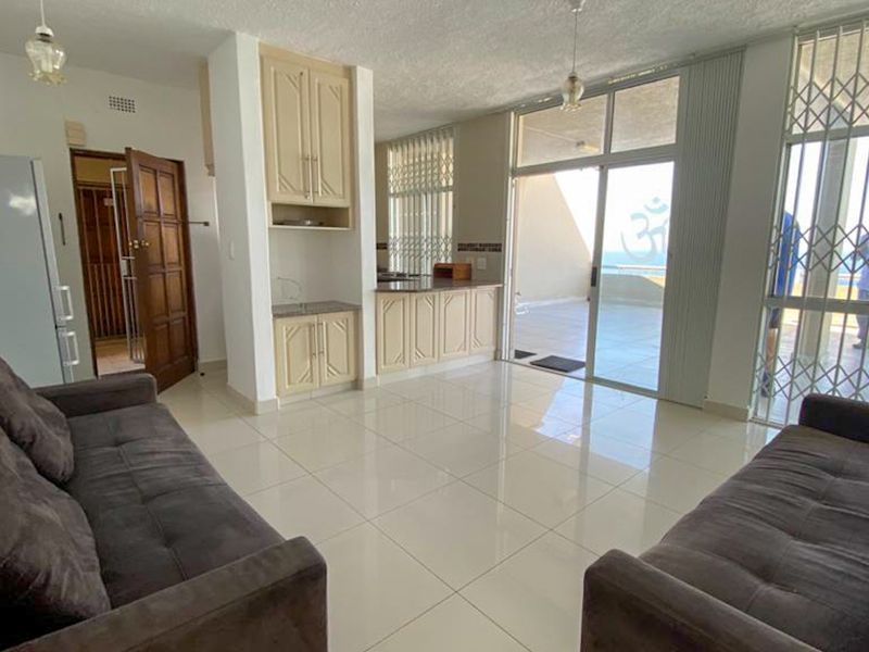 Open plan living area featuring tiled floors, built-in cabinetry, and large sliding glass doors leading to an outdoor balcony with security gates.