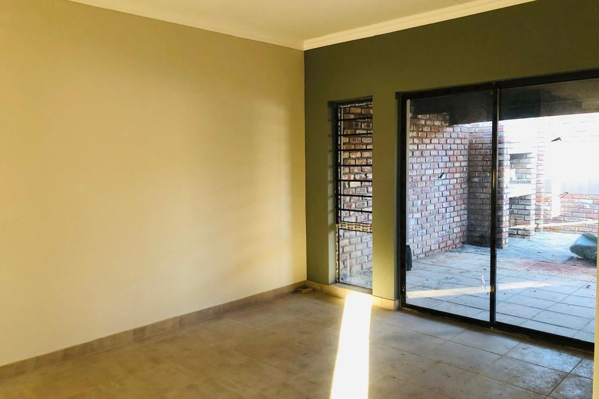 An empty living room featuring tiled flooring and a sliding glass door providing direct access to an outdoor patio area.