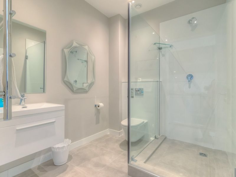 Modern bathroom featuring a wall-mounted vanity, wall-hung toilet, and a spacious glass-enclosed shower with contemporary tiled finishes.