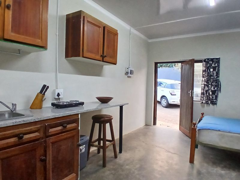 Open-plan studio space featuring a compact kitchenette with wooden cabinetry, laminate countertops, and direct access to the exterior.