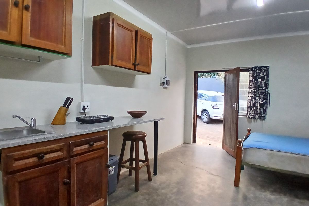 Open-plan studio space featuring a compact kitchenette with wooden cabinetry, laminate countertops, and direct access to the exterior.