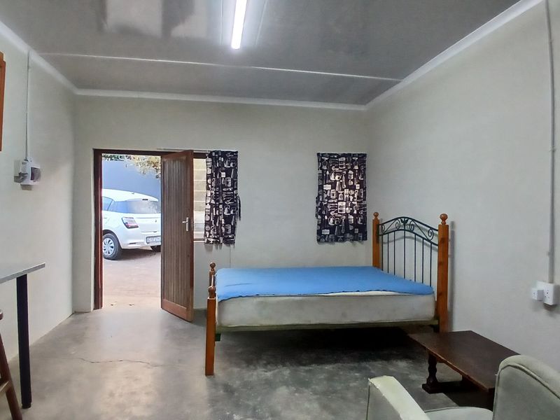 Open-plan studio space featuring concrete flooring, basic wooden cabinetry, and direct exterior access, suitable for renovation or modernization.
