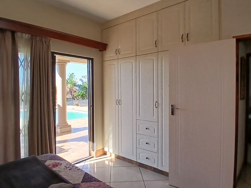 Bedroom featuring built-in cupboards, tiled flooring, and direct access to an outdoor patio area with pool views.