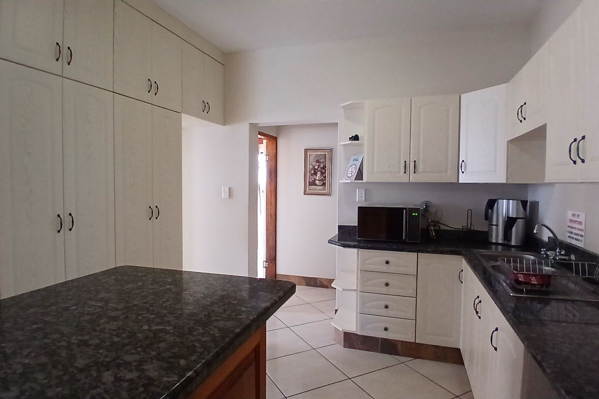 A functional kitchen featuring ample built-in cabinetry, granite countertops, tiled flooring, and a double sink, offering a practical layout for daily use.