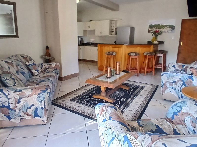 Open plan living area featuring a kitchen with built-in cabinetry and a breakfast bar, finished with tiled flooring throughout.