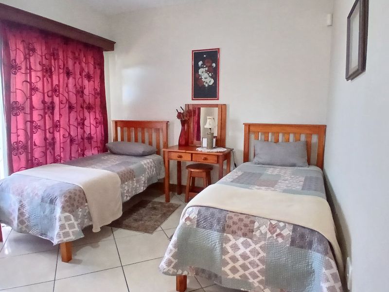 A bedroom featuring tiled flooring and a sliding glass door with curtain access, providing natural light and outdoor connectivity.