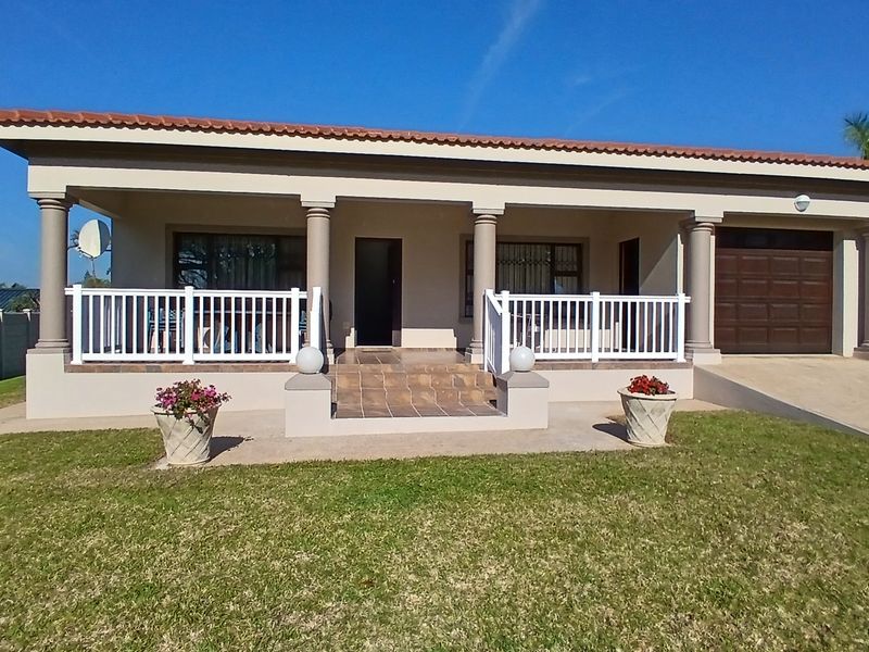 Front elevation of a single-story house featuring a covered patio with tiled steps, concrete columns, white balustrades, and an integrated garage.
