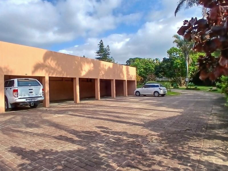 A row of covered parking bays with a paved driveway area, providing convenient off-street parking for residents.