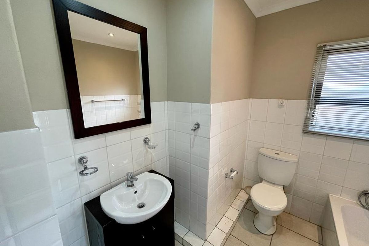 A functional bathroom featuring a vanity basin, toilet, and tiled wall finishes with a neutral color palette.