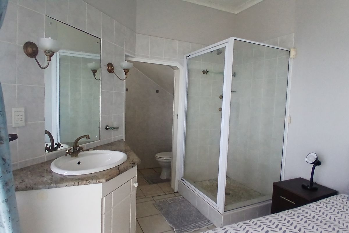 En-suite bathroom featuring a vanity with granite countertop, glass shower enclosure, and a separate toilet area with tiled finishes.