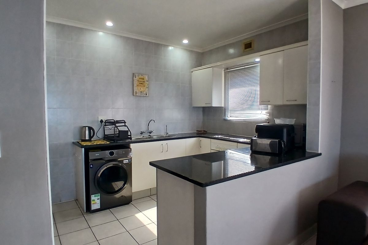 A functional kitchen featuring granite countertops, ample built-in cabinetry, a breakfast bar, and tiled finishes, providing a clean and practical workspace.