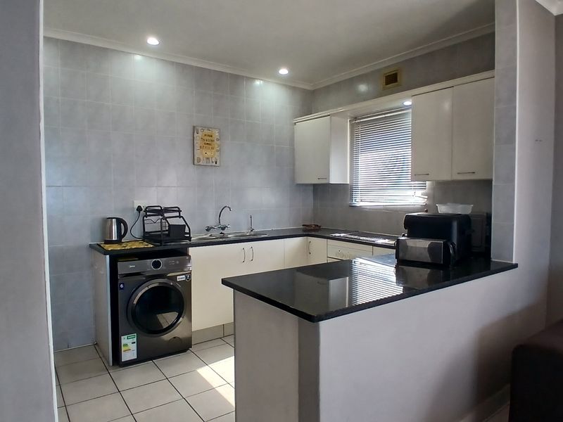 A functional kitchen featuring granite countertops, ample built-in cabinetry, a breakfast bar, and tiled finishes, providing a clean and practical workspace.