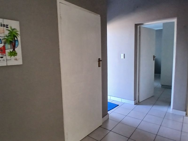 A functional hallway featuring neutral grey walls and tiled flooring, providing access to multiple rooms within the apartment.