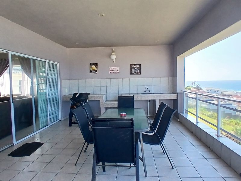 Spacious covered balcony featuring a built-in braai area, sink, and panoramic ocean views, perfect for outdoor entertaining.