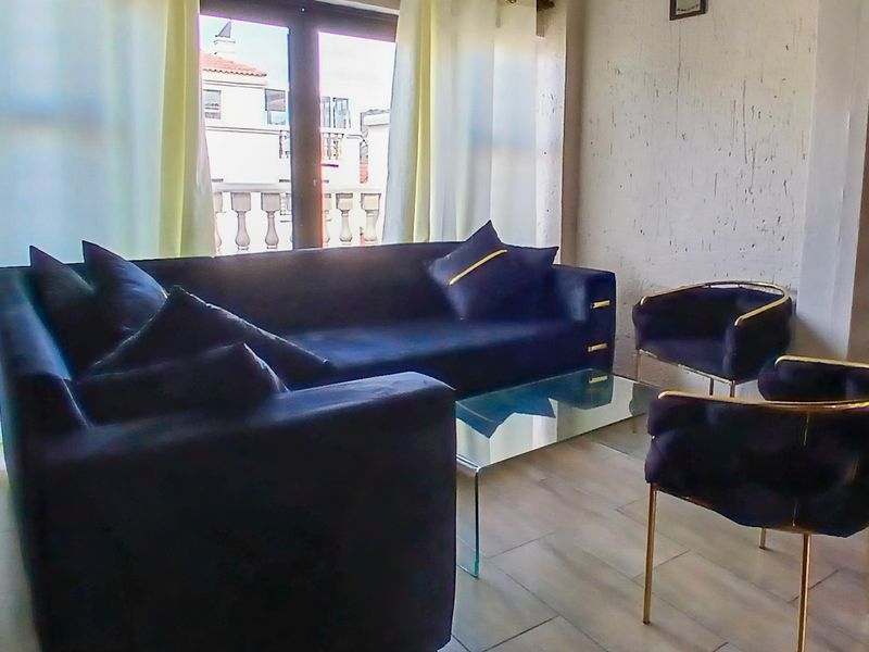 A living room area featuring tiled flooring and a sliding glass door leading to a balcony, with visible wall surface wear.