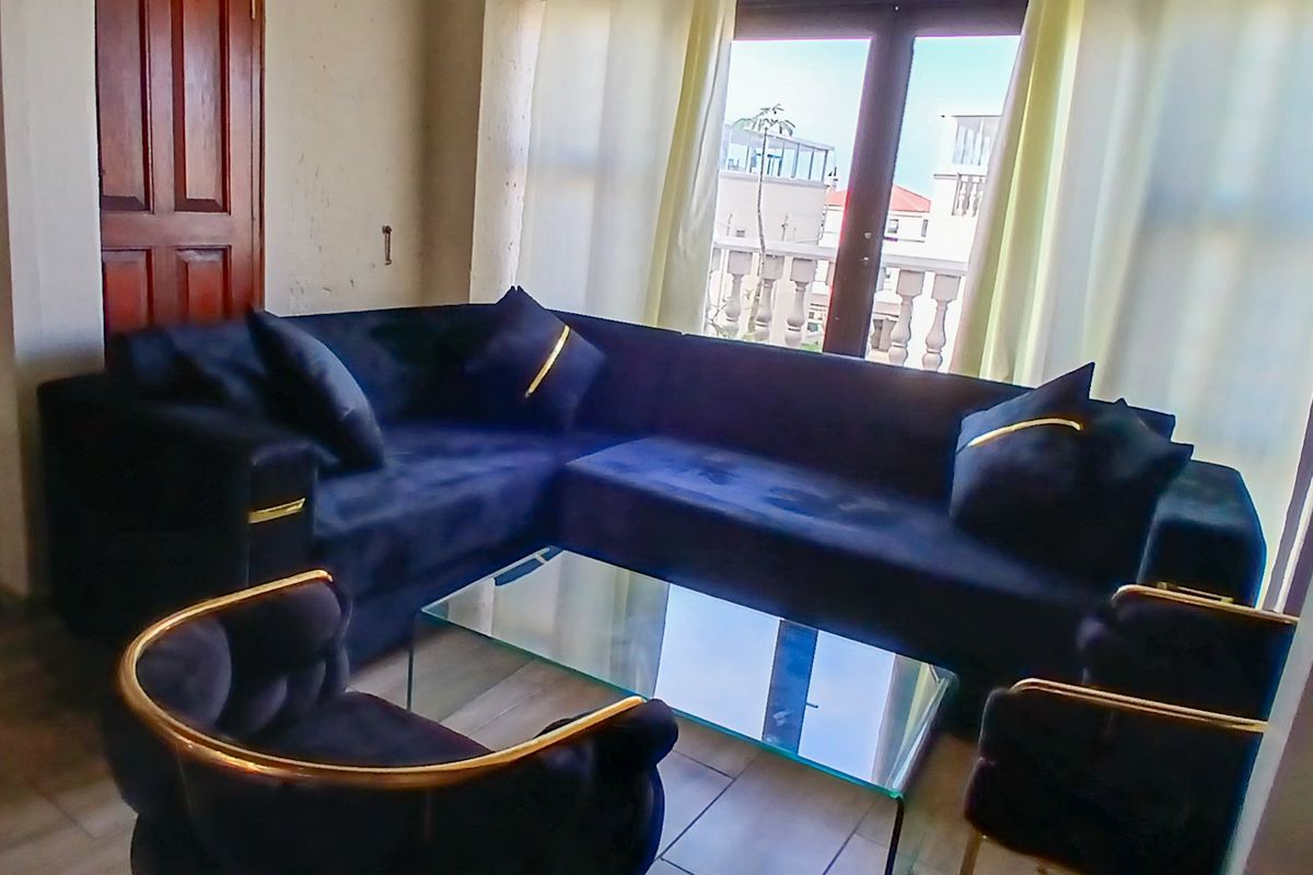 A living room area featuring tiled flooring and double glass doors leading to a balcony with a balustrade.