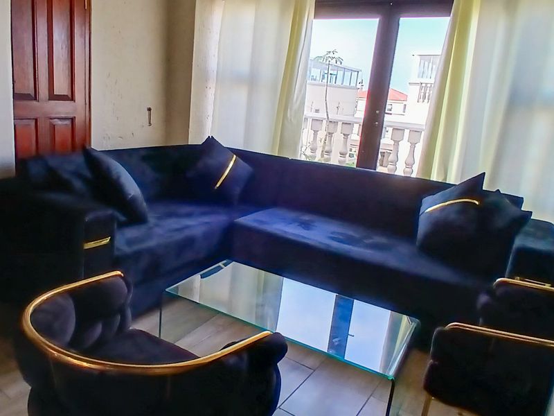 A living room area featuring tiled flooring and double glass doors leading to a balcony with a balustrade.