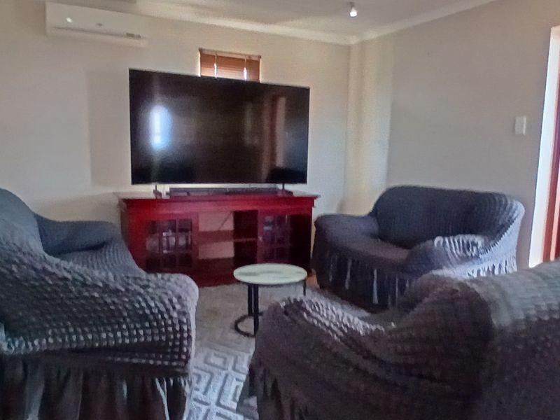 A living room featuring a wall-mounted air conditioning unit, coving, and a timber door leading to an adjacent space.