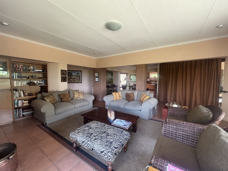 Spacious open-plan living area featuring built-in shelving and tiled flooring, providing a versatile layout for comfortable family living.