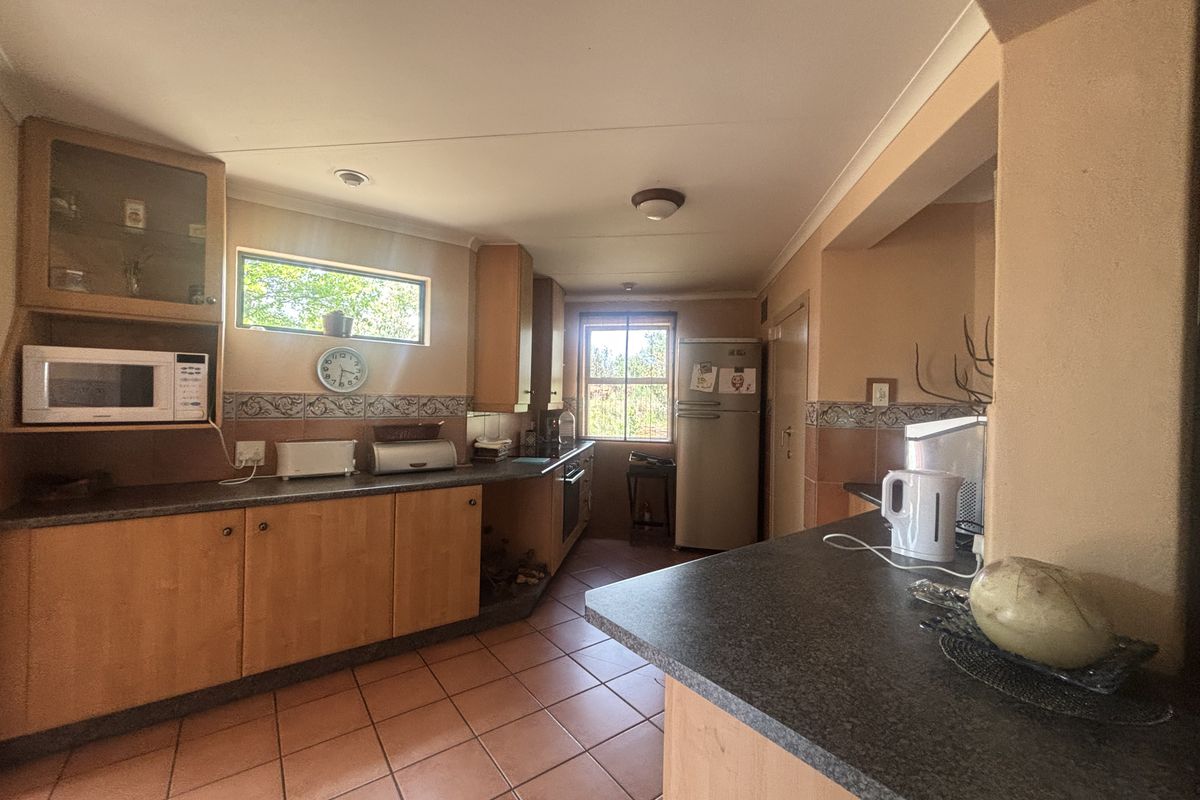 A functional kitchen featuring wooden cabinetry, dark laminate countertops, tiled flooring, and a built-in oven with an integrated microwave space.