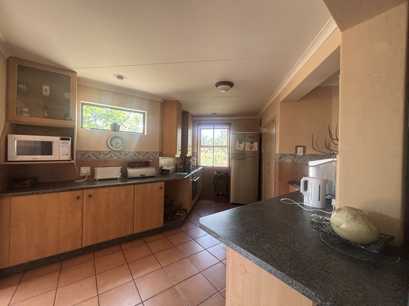 A functional kitchen featuring wooden cabinetry, dark laminate countertops, tiled flooring, and a built-in oven with an integrated microwave space.