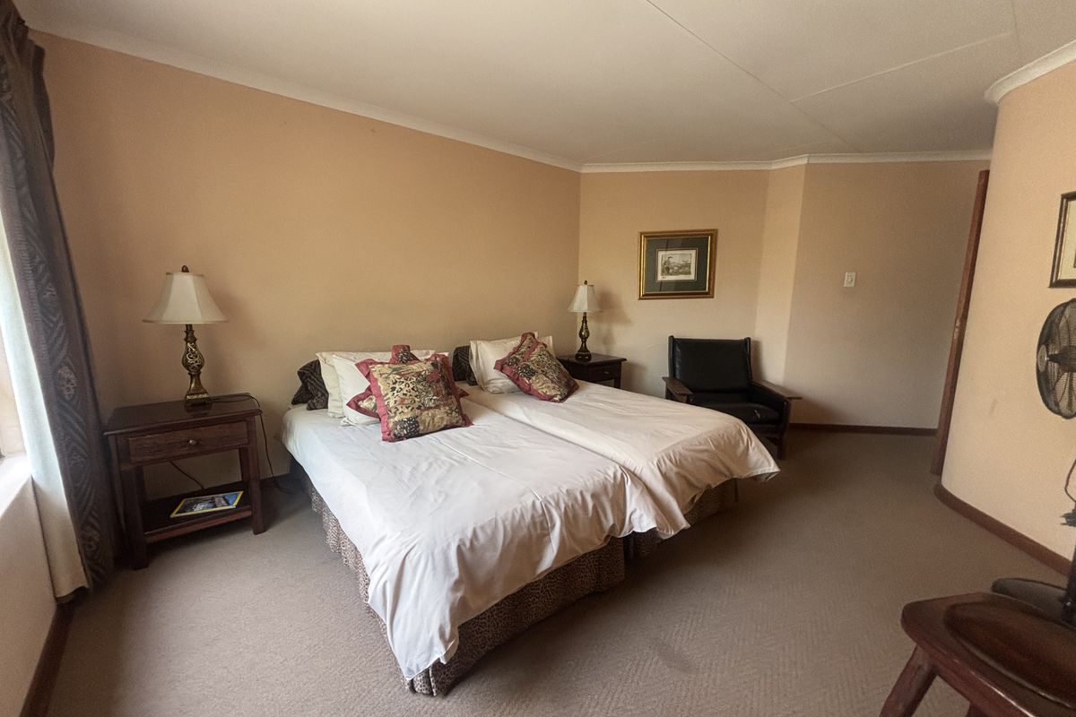 A spacious bedroom featuring neutral wall tones, carpeted flooring, and coved ceiling detailing, providing a comfortable and functional sleeping area.