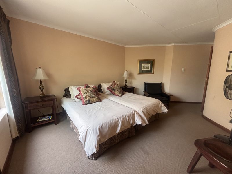 A spacious bedroom featuring neutral wall tones, carpeted flooring, and coved ceiling detailing, providing a comfortable and functional sleeping area.