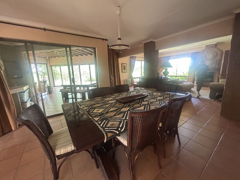 Spacious open-plan dining and living area featuring tiled flooring, large sliding glass doors leading to a patio, and a feature fireplace.