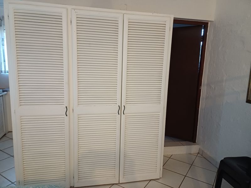 Bedroom featuring built-in louvered door wardrobes and ceramic tiled flooring, requiring minor cosmetic updates to the wall finishes.