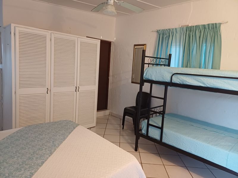 A bedroom featuring tiled flooring, a built-in wardrobe with louvered doors, and a ceiling fan.