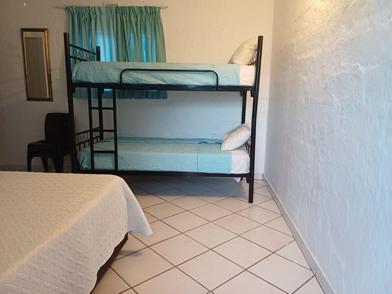 A bedroom featuring tiled flooring and textured walls, currently configured with a bunk bed setup.