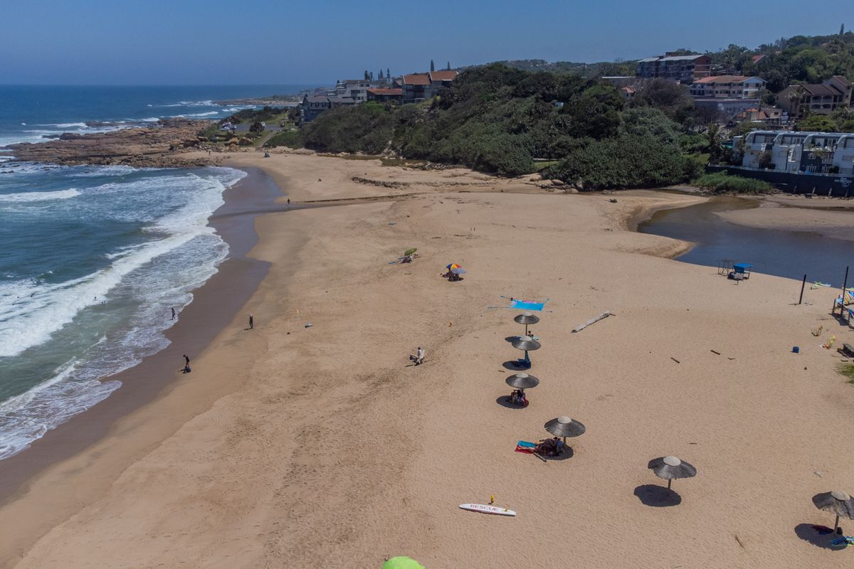 Aerial view of the coastal beach area, showcasing the shoreline, ocean, and surrounding landscape.