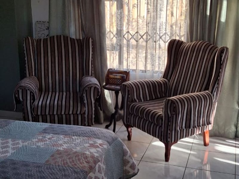 A bedroom featuring tiled flooring and a window fitted with a security gate and curtain rails.